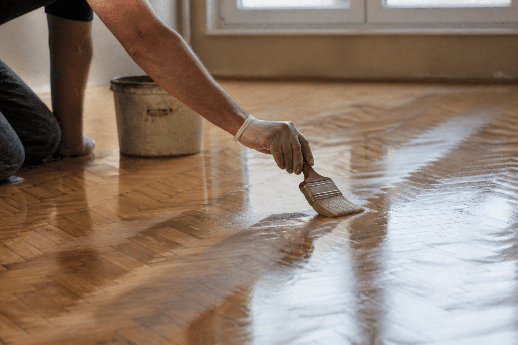 Main appliquant cire brillante sur parquet en bois