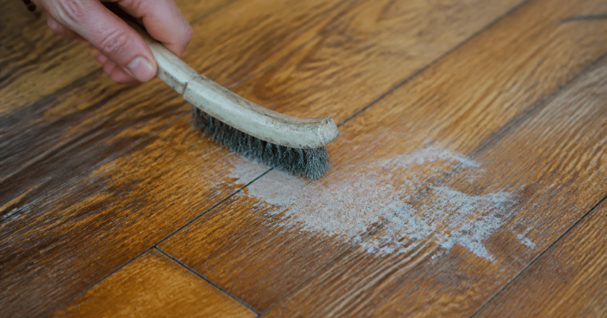 Brosse metallique grattant tache blanche sur plancher bois