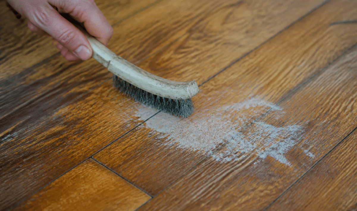 Brosse metallique grattant tache blanche sur plancher bois