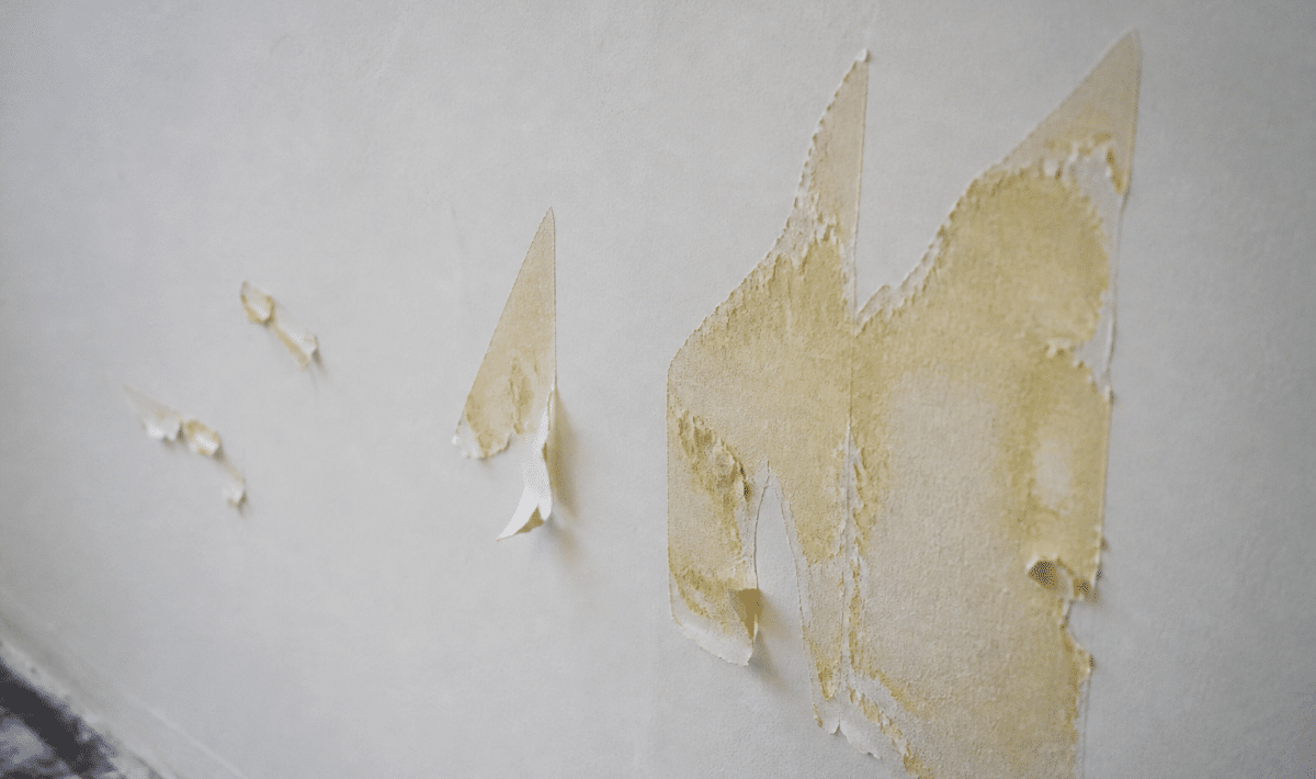 Mur blanc avec résidu colle jaune décollé partiellement