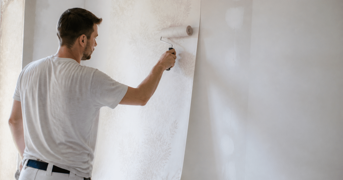 Ouvrier applique papier peint sur mur blanc avec rouleau
