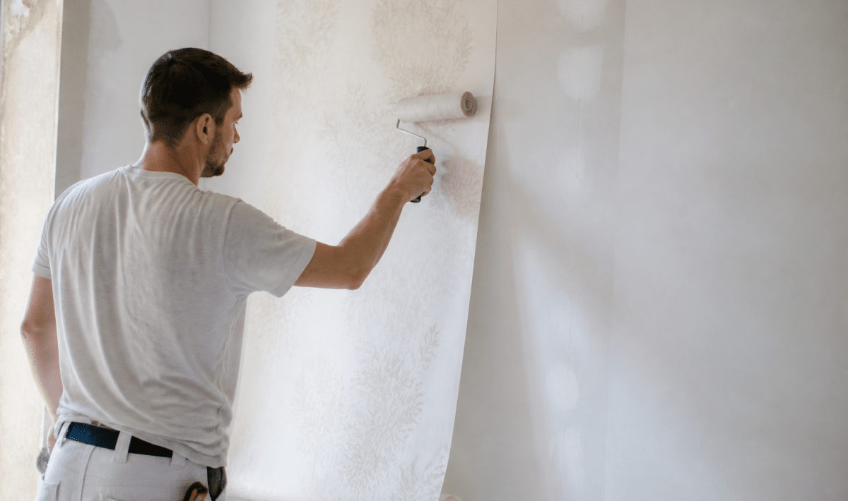 Ouvrier applique papier peint sur mur blanc avec rouleau