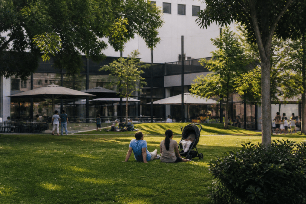 Parc verdoyant avec familles, commerces en arrière-plan urbain