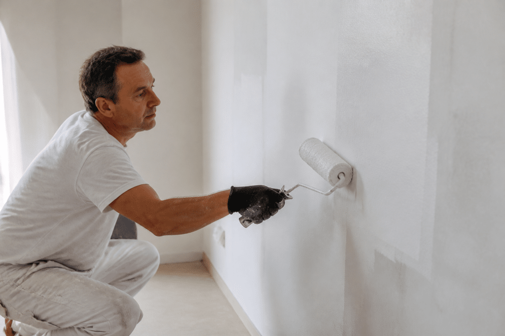 Peintre appliquant peinture blanche sur mur avec rouleau