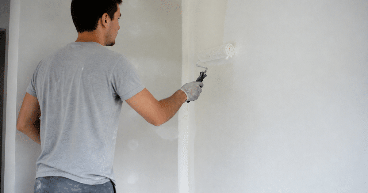 Peintre appliquant peinture blanche sur mur interieur avec rouleau