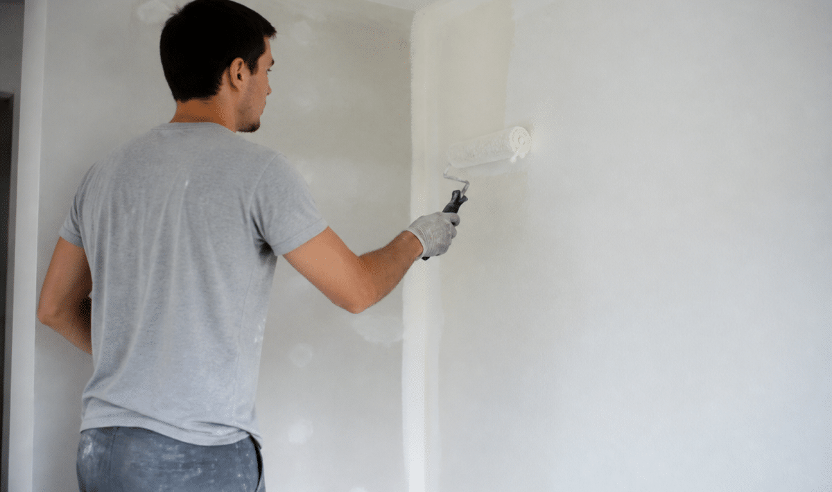 Peintre appliquant peinture blanche sur mur interieur avec rouleau