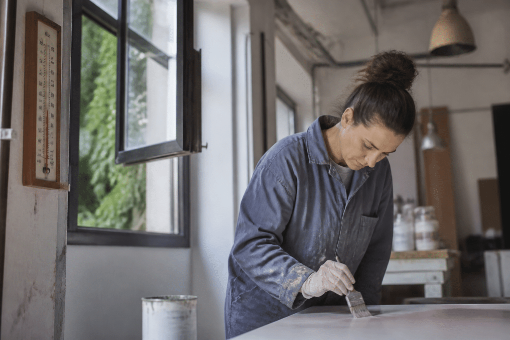 Peintre appliquant peinture dans atelier bien ventile thermometre visible