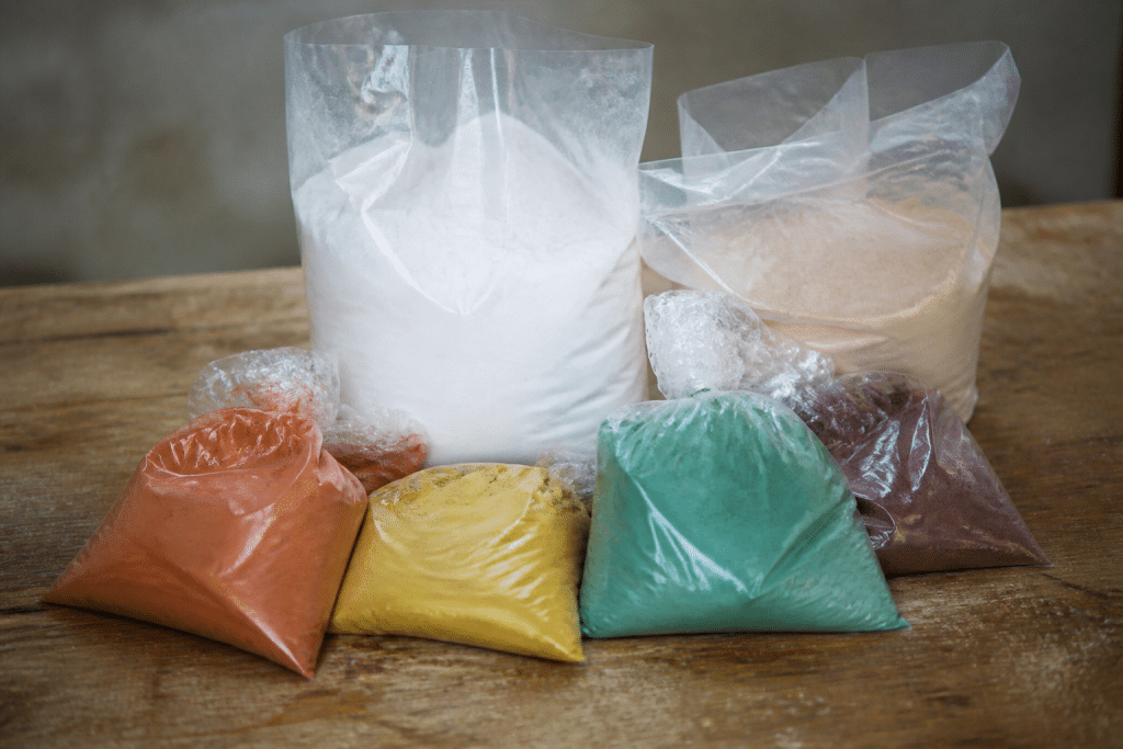 Sacs poudre blanche et pigments colorés sur table bois