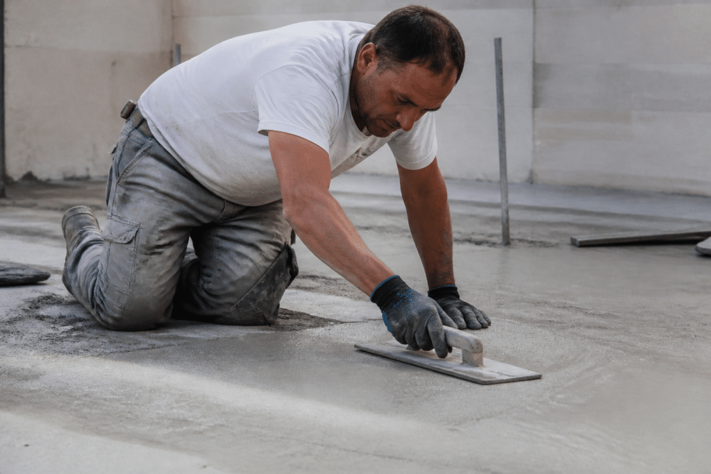 Ouvrier lissant sol béton avec truelle grise