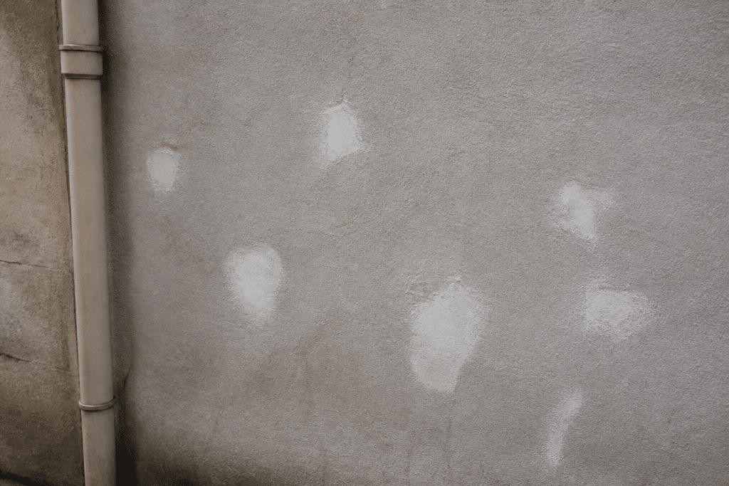 Mur gris avec trous rebouchés à l'enduit blanc