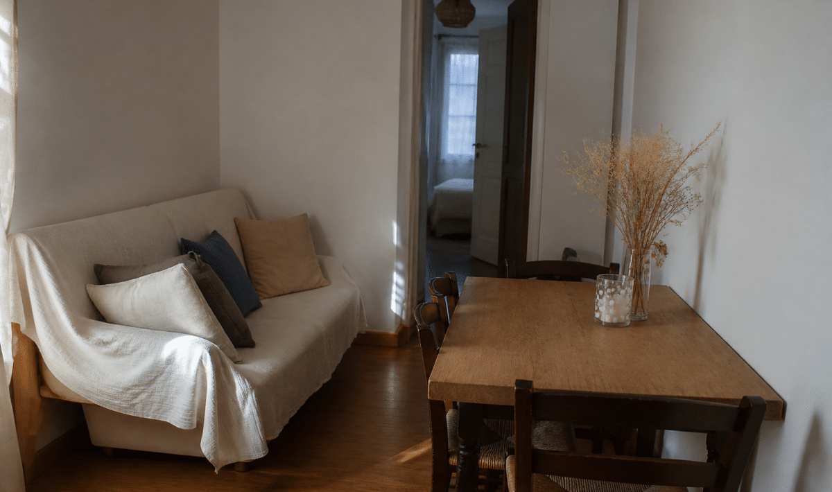 Petit salon-salle a manger avec canape et table contre murs