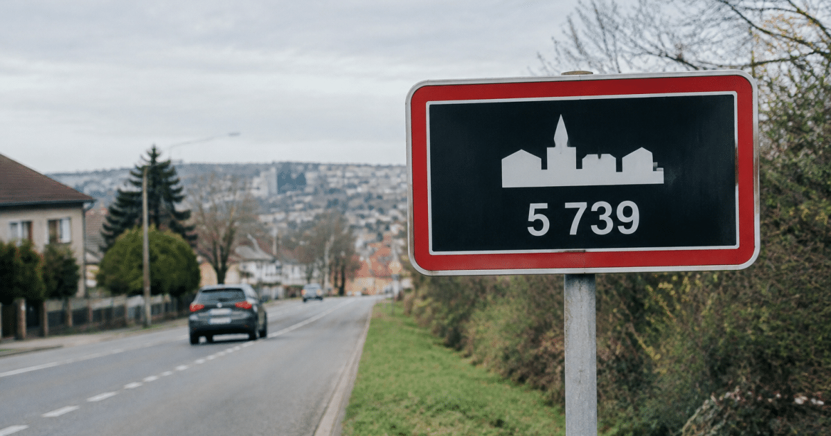 Panneau routier affichant la population de Longwy en chiffres blancs