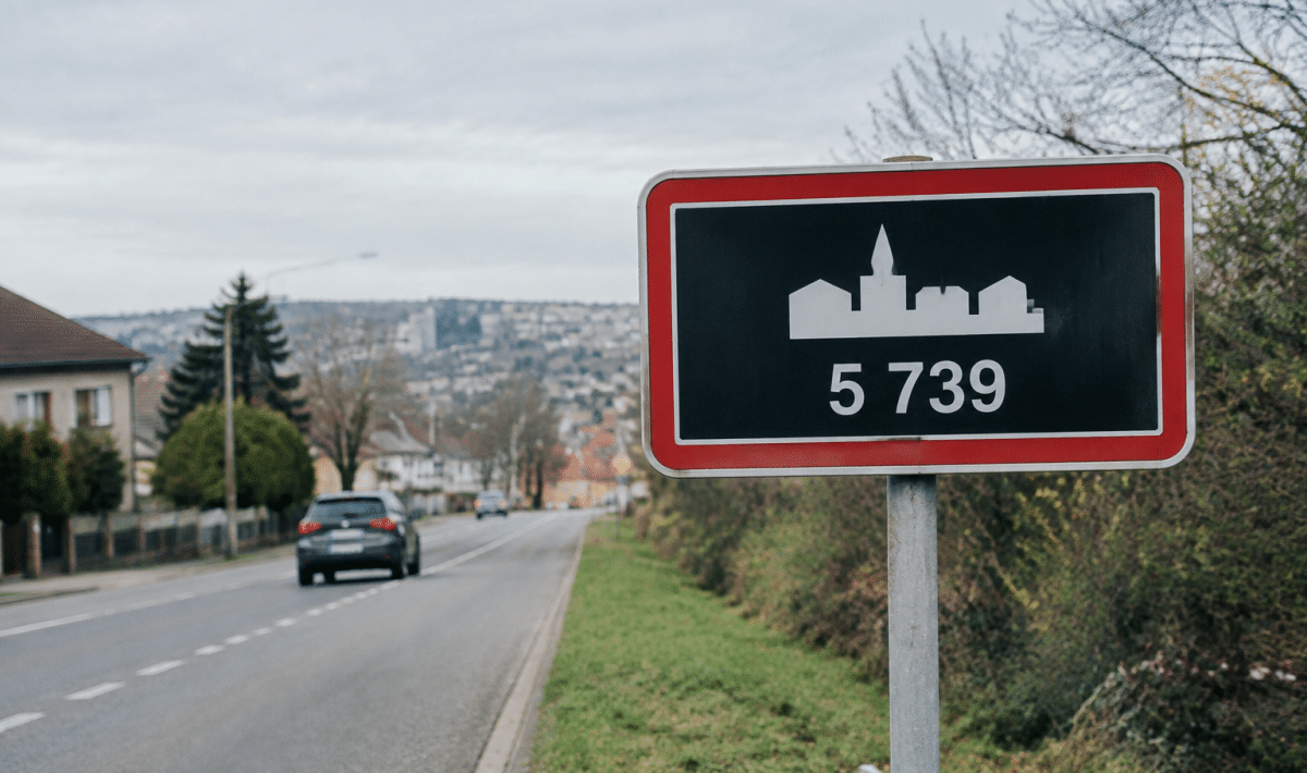 Panneau routier affichant la population de Longwy en chiffres blancs
