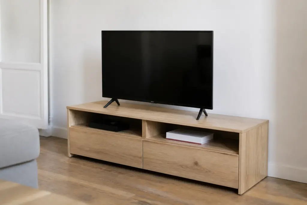 Meuble TV bois clair avec tiroirs contre mur blanc